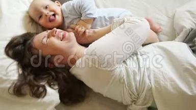 <strong>阳光</strong>家庭早晨妈妈和<strong>宝宝</strong>在床上。 一个女人挠痒痒，拥抱她一岁的儿子。 母亲节